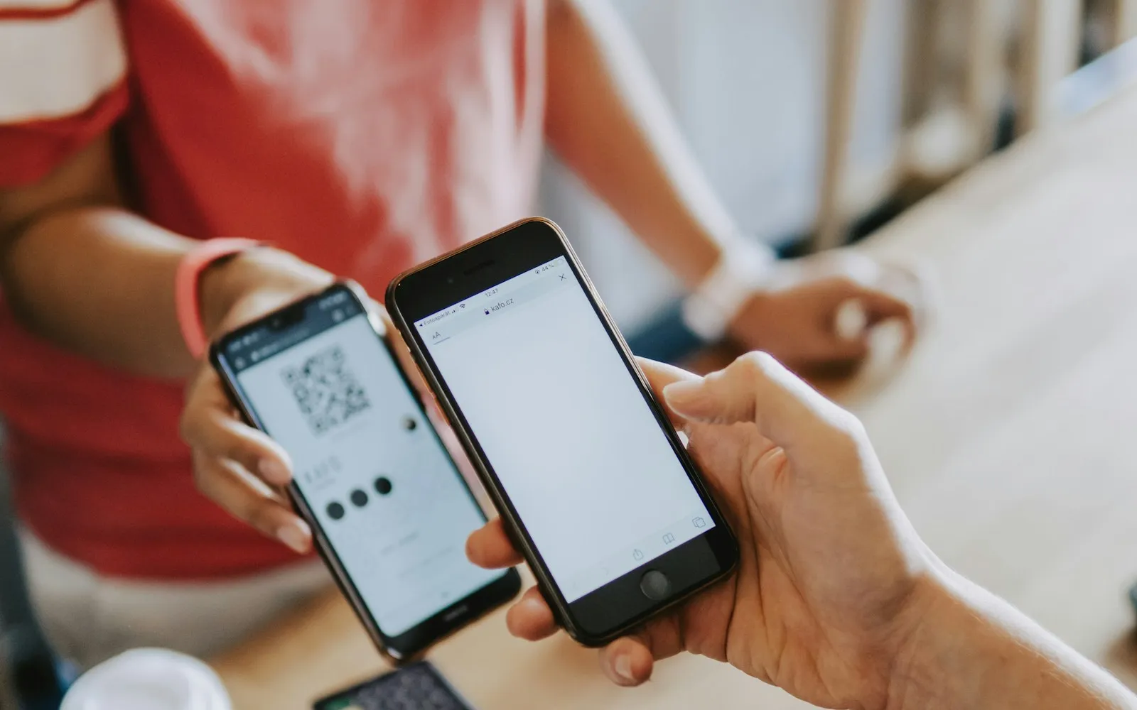 Two people holding phones toward each other, one screen showing a QR code, the other a blank browser page